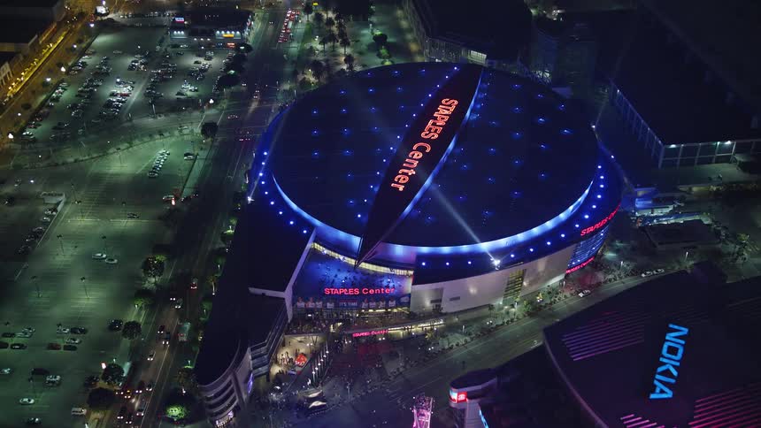 Aerial panorama of a metropolis with skyscrapers in an illuminated staples center stadium at night