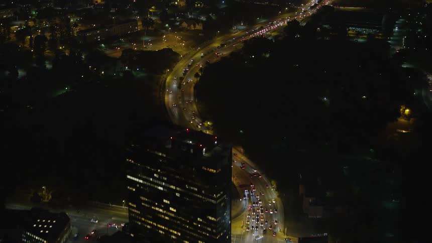Aerial of busy street connected between two business districts in the city at night
