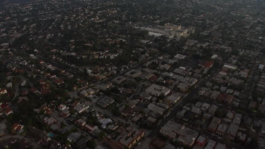 Aerial view of neighborhood rooftops and city skyline on horizon at dusk