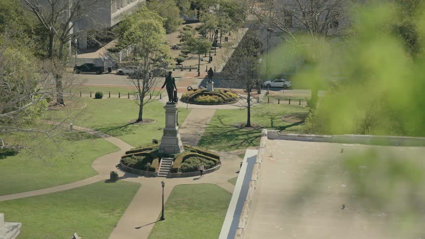 Top view of a person walking through a square with a statue during the day
