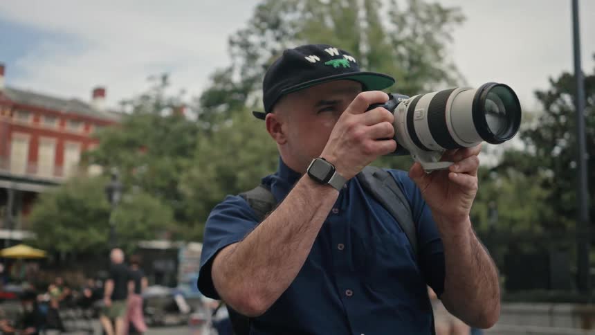 A photographer uses a camera with a large lens in the city