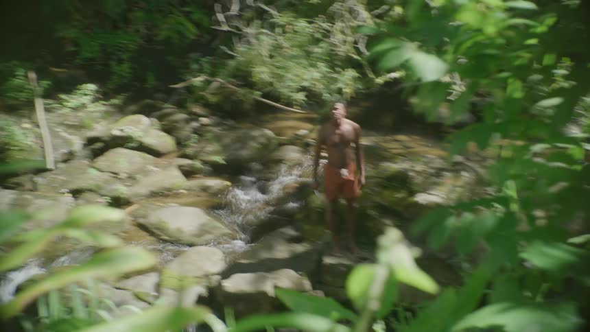 A man exercising in a forest near a stream