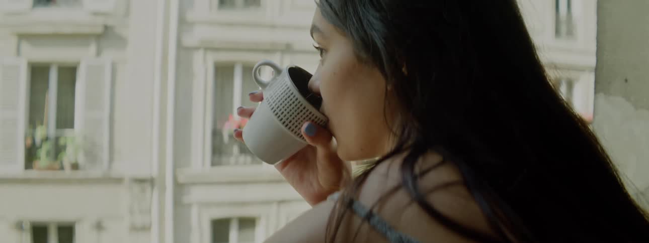Young woman drinking coffee in the balcony