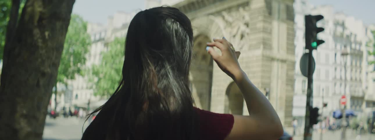 A young woman pointing towards the arc de triomphe