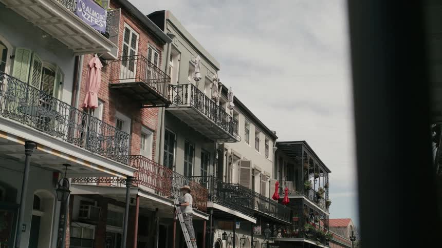 Residential buildings with a man on a ladder painting the porch railing
