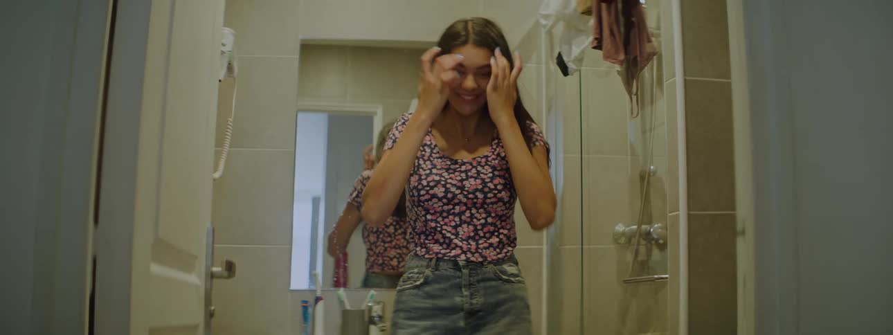 Young woman in front of the mirror in the bathroom trying on and modeling their look