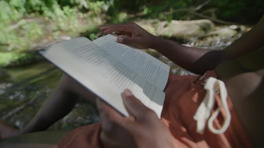 A man is sitting in the stream reading