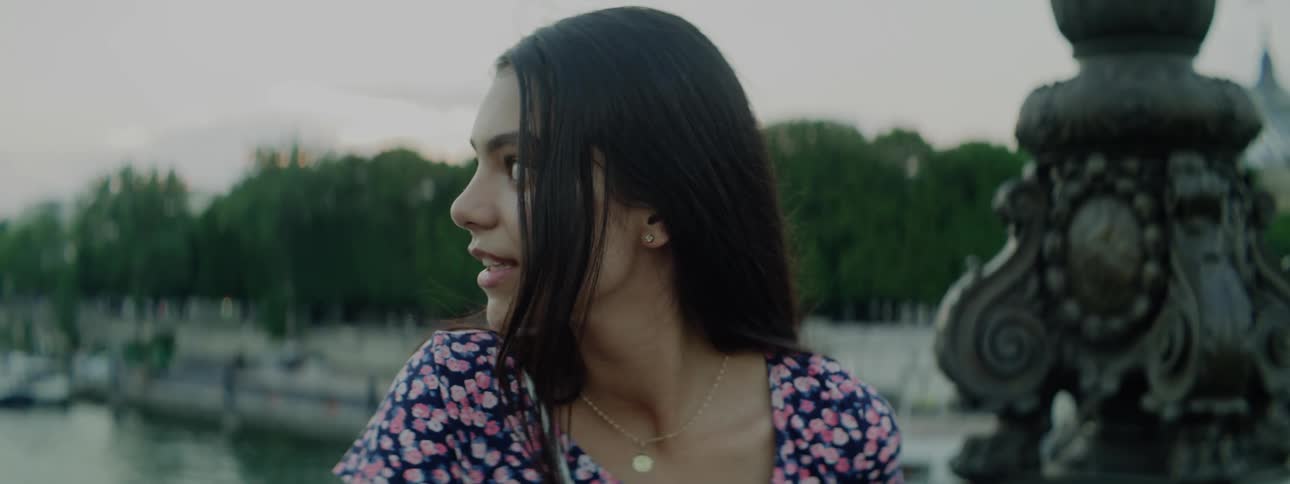 Young girl stands on a bridge next to a pier talking to the camera
