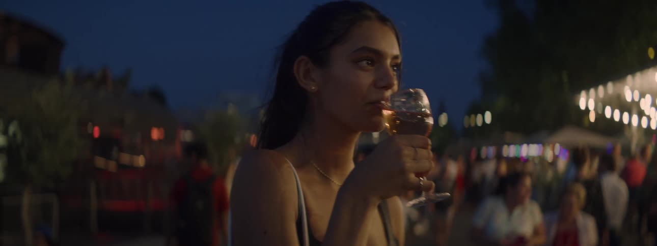 A young woman is drinking a glass of wine at a fair