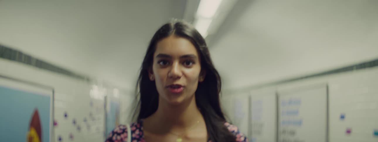 Woman walks down a school hallway while talking