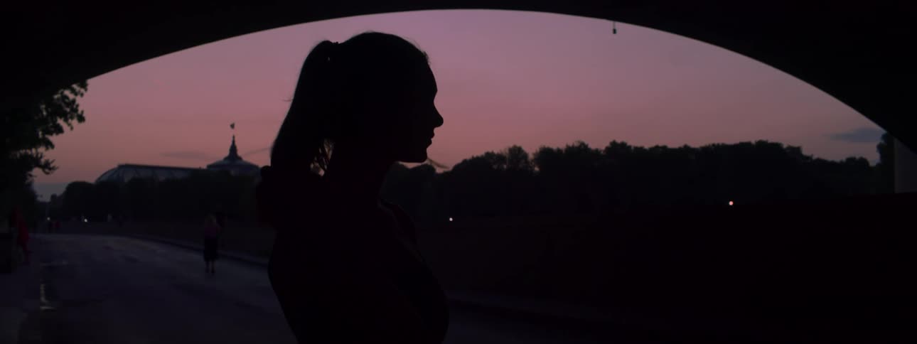 A woman is standing under the overpass