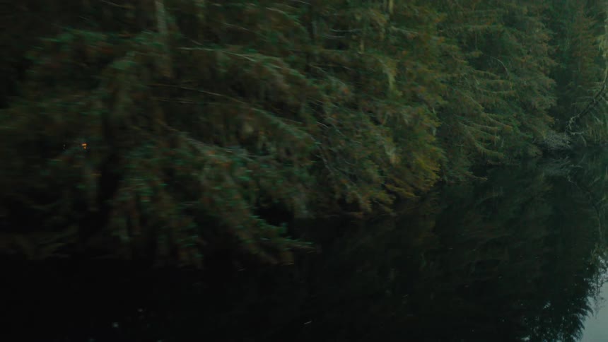Aerial view of a black car driving on a road in the mountains