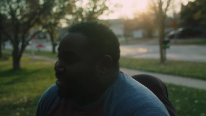 A black man sitting outside laughs and talks