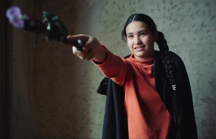 A girl waves and points a flower