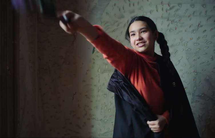 A child waves a wand by the wall
