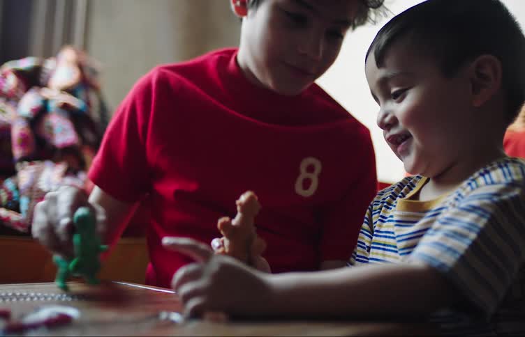 Smiling brothers play together with toy dinosaurs