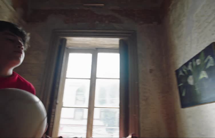 A boy throws a soccer ball against the wall
