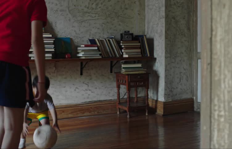 Two boys a toddler and a teenager play soccer inside an old house
