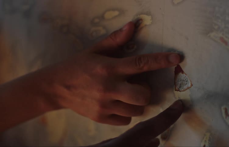 Two human hands are fingering a hole in a wall