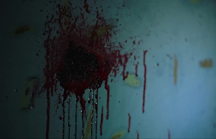 Closeup on a wall with blood marks seen by flashlight light
