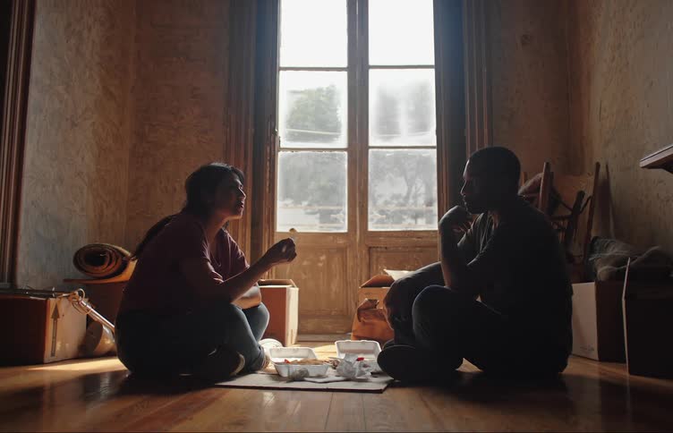 Couple sitting on the floor of a laminate floor while eating lunchboxes