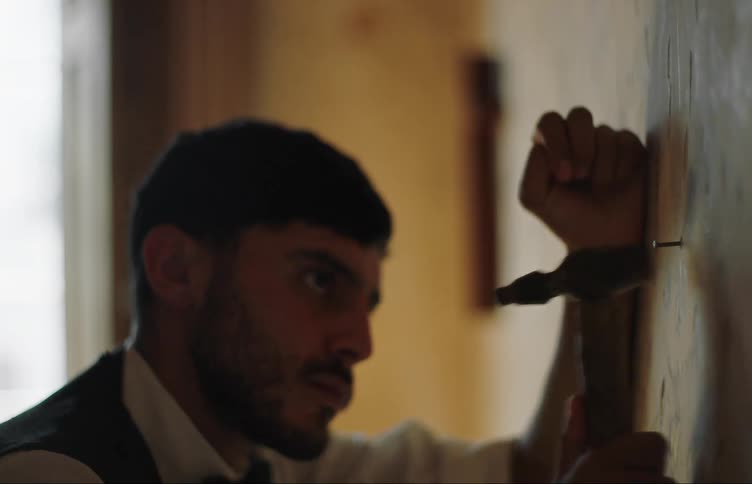 Man hammers nail into wall papered wall