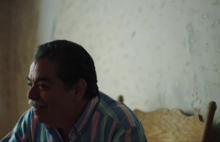 A man sits indoors talking and laughing