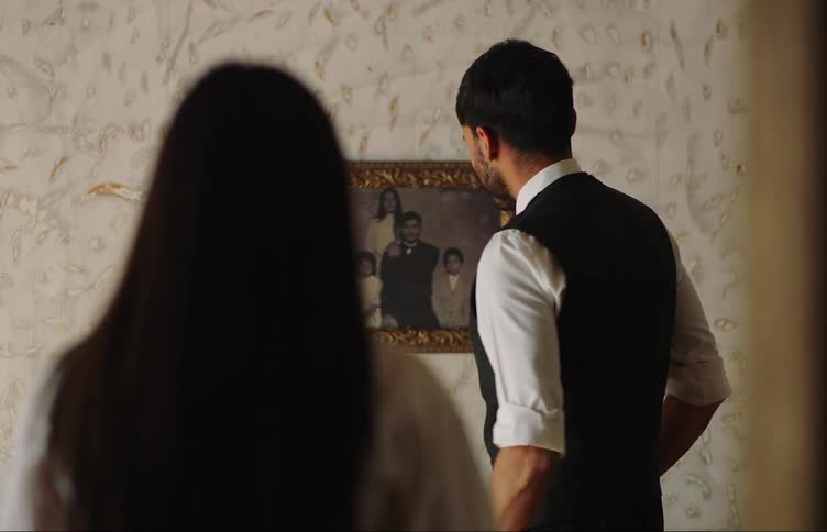 Man placing a photo frame on a wall with the help of a woman