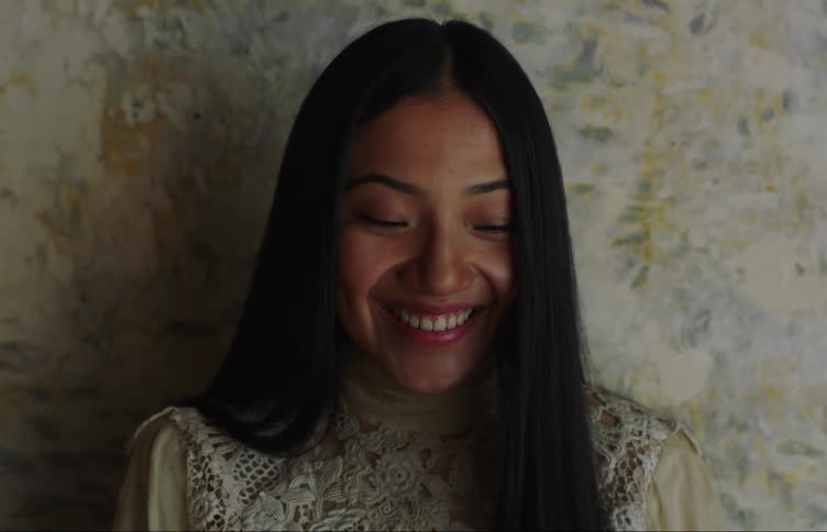 A woman smiles while in front of a wall