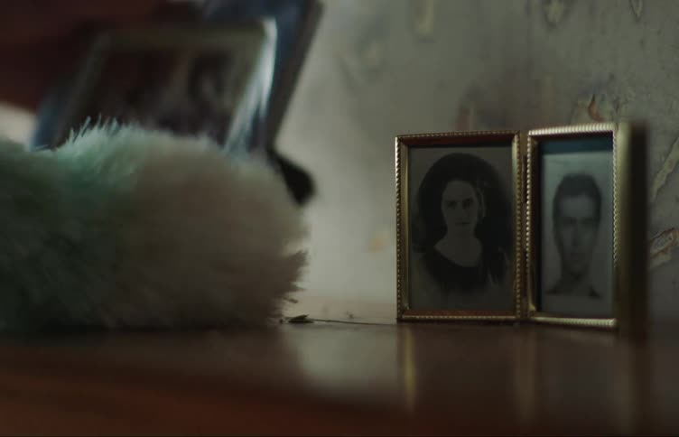 Cleaning around three framed pictures on a wooden shelf
