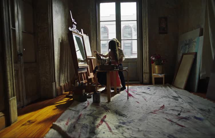 Daughter runs into art studio where her mother is painting and is pulled onto her mothers lap