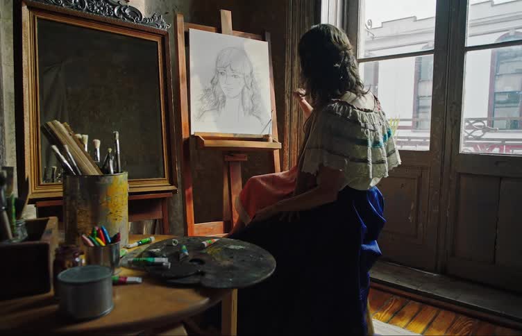 Female artist holds her daughter in her lap and teaches her how to draw