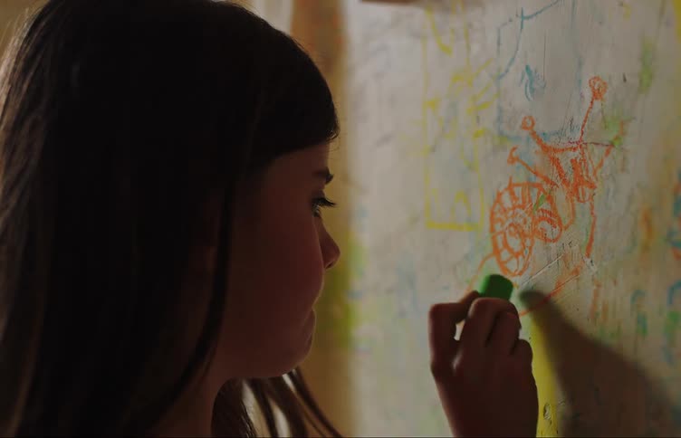 Girl drawing on a colorful scribblecovered wall