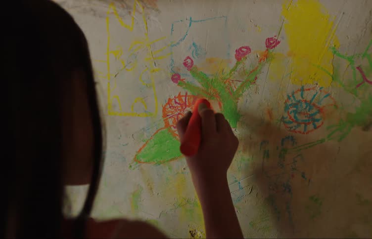 A little girl with a crayon drawing on a wall