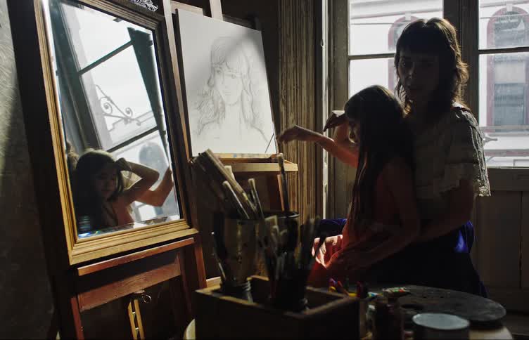 A woman is teaching a child how to sketch on an easel