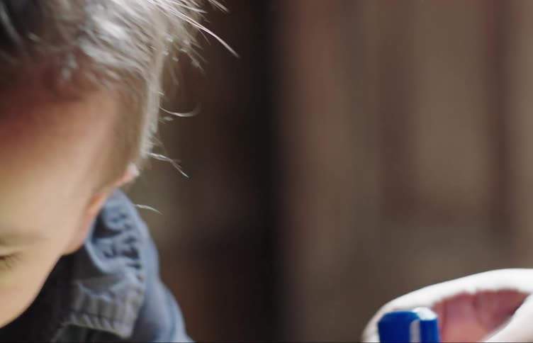 A baby crawls over to a hand offering him building blocks