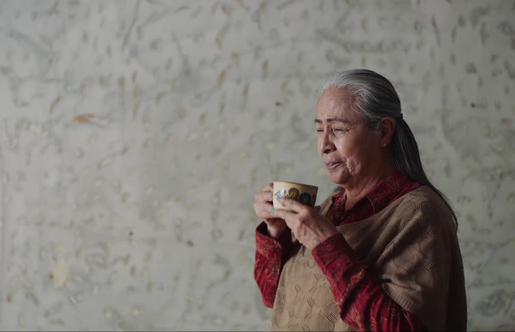Elderly lady drinking a mug while standing