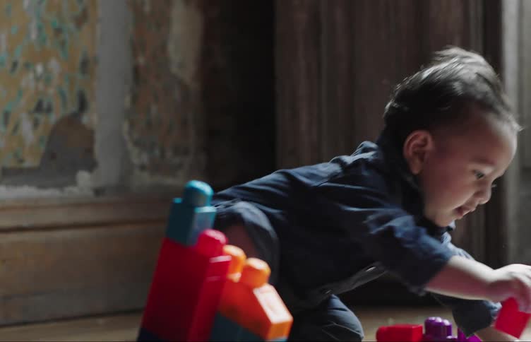 Baby sitting on the floor playing with some plastic toys and smiling