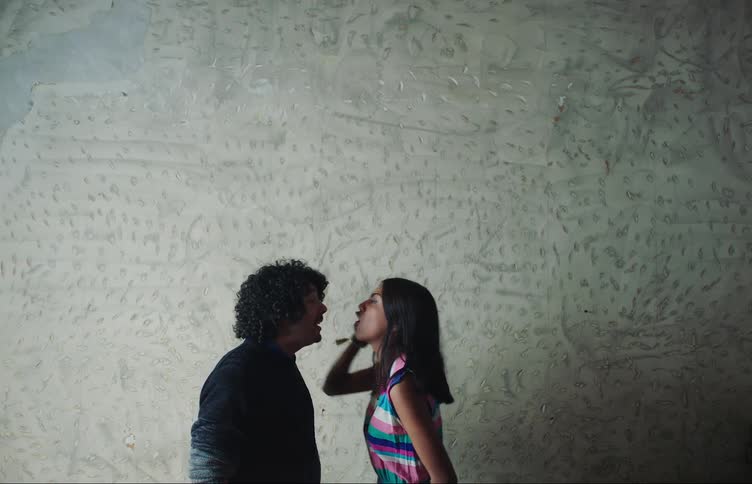 A couple of teenagers have a heated argument in front of a grey textured wall