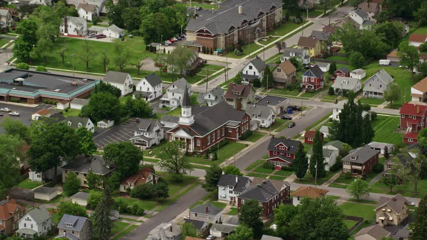 Aerial panorama of a residential neighborhood with tree vegetation and a central church