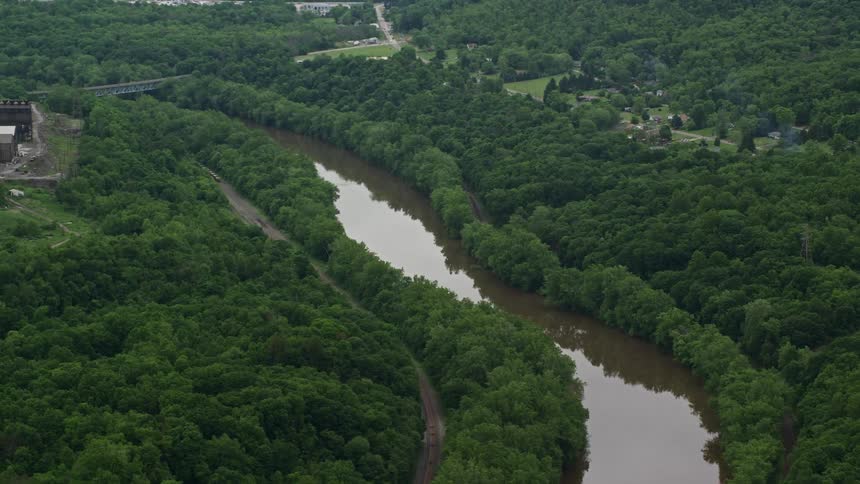 Aerial panorama of a river channel in a place with vast vegetation rural houses and factories