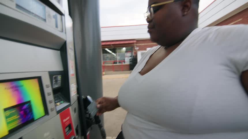 Woman inserting her card and typing at a fuel pump at a gas station