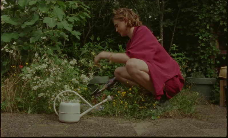 A woman angrily digs in a garden