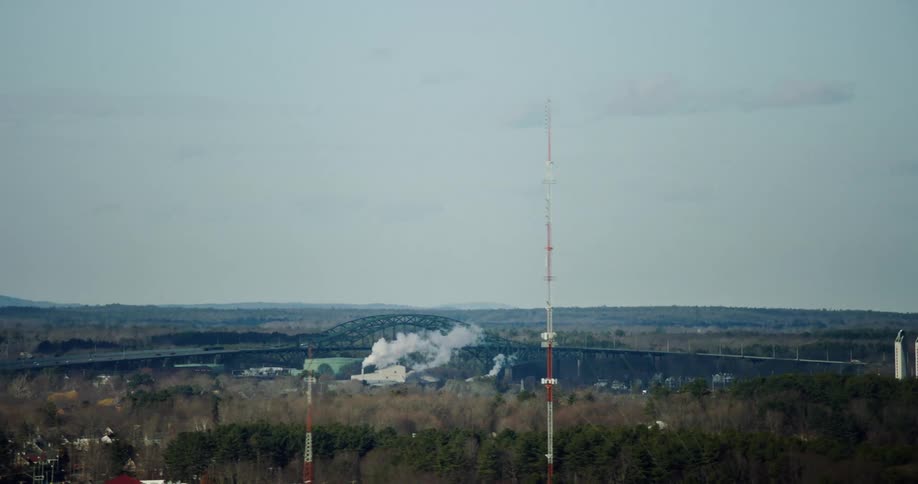 Smoke rises up and through a bridge in a rural area