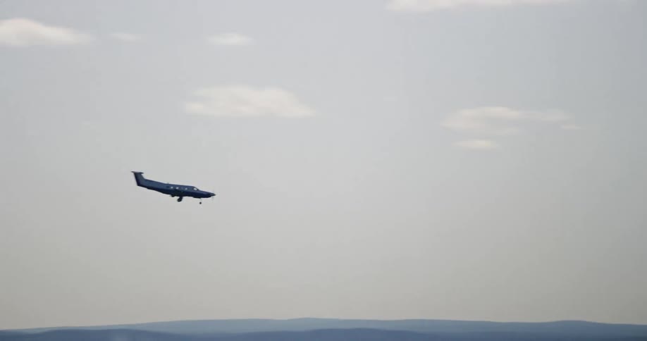 A small singleengine airplane with two propellers is flying above the countryside