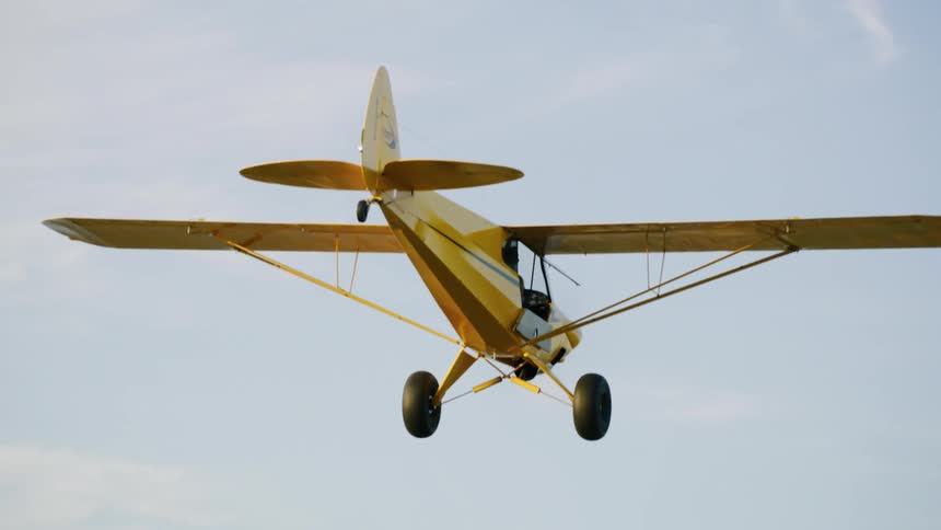 A small yellow singleengine plane flying over the sky