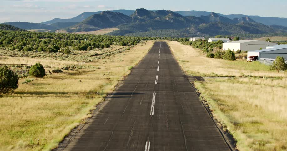 Runway passes between air hangers and forests near mountains