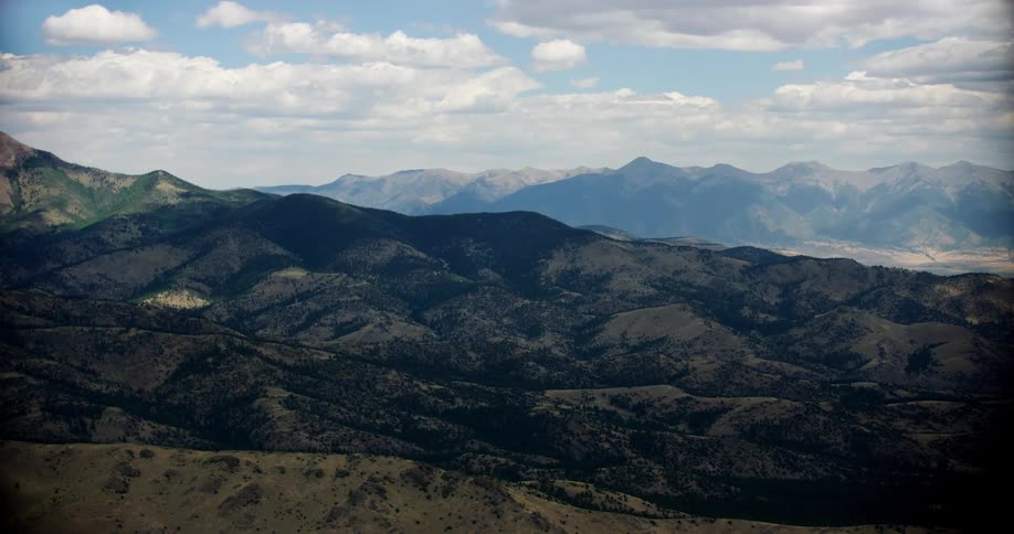 Several vast mountain ranges under a cloudy sky