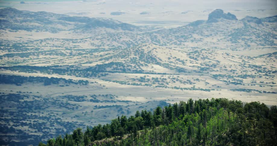 Aerial panorama of a mountain peak covered by forests and natural hills in the background during the day