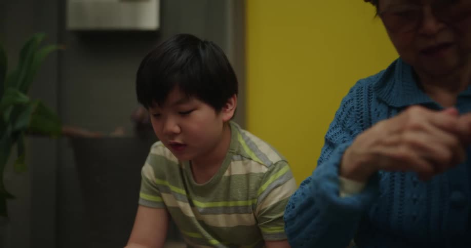 Elderly man holding a tablet sitting next to a boy